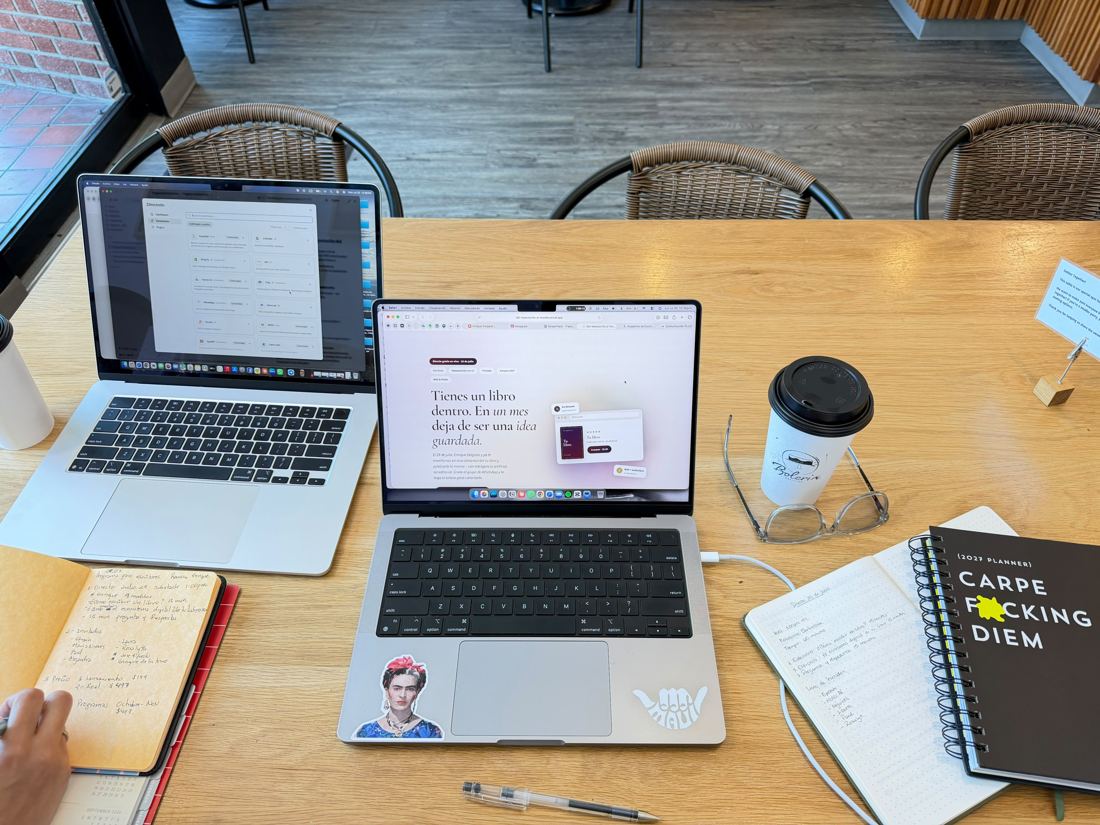 Mesa de trabajo con dos laptops, libretas y café